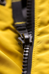 Zipper on clothes close-up. black color. Bright yellow jacket