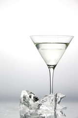 Glass with martini and several pieces of melting ice isolated on a neutral background