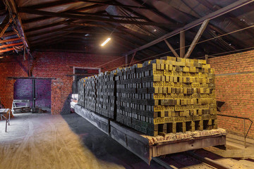 Production of clay bricks at a brick factory. Molded dried bricks stacked on pallets are load to...
