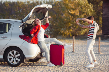 Obraz premium Young couple traveling on the car. Woman and man having a trip on automobile. Happy young people outdoors.