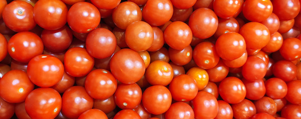 a large number of red small cherry tomatoes in a heap, background