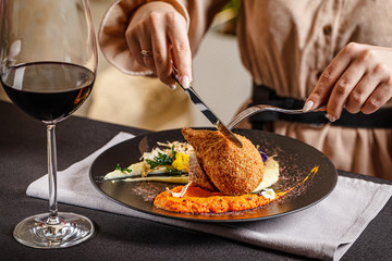 Modern Ukrainian, European cuisine. The girl eats a meatball in Kiev and drinks red wine in a restaurant. In the hands of a knife and fork. background image, copy space text