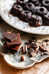 Different kind of delicious organic pieces of chocolate put in a stack. Vintage kitchen tableware, nuts as decor. Close up, macro, front view
