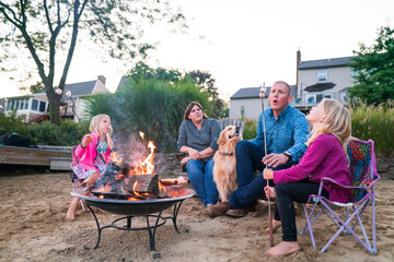 Family roasting marshmallows around a fire outdoors