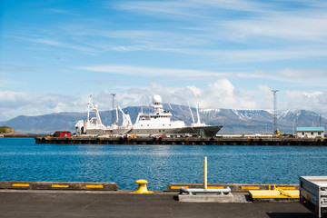 A large white ship in one of the harbors at Reykjavik, Iceland with a view of a mountain range in the distance