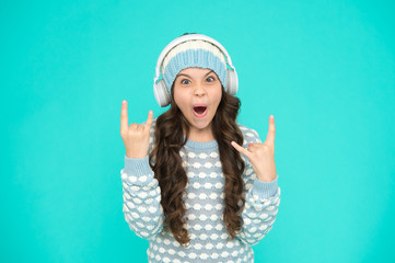 create feel-good playlist. music mood. little child knitted sweater and hat. musical suggestions for winter playlist. her favorite winter songs. surprised girl enjoy winter playlist in headphones