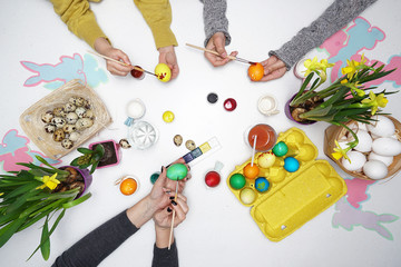 Top view of the hands that paints Easter eggs. Happy family are preparing for Easter.