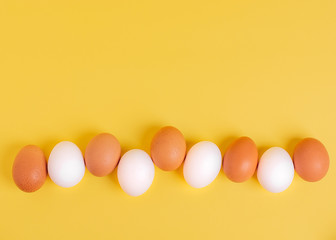Easter concept. White and brown eggs on a yellow background. Copy spase, top veiw