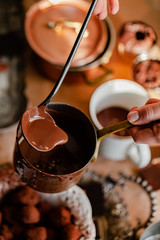 Fototapeta premium Process of preparation of delicious organic hot chocolate in old vintage ladle. Soft daylight, lifestyle photography, process of tasty drink creation. Close up, macro