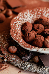 Homemade delicious dark chocolate  truffles. Served in white vintage plate, sprinkled with cocoa powder. Delicious elegant dessert for sweet-tooth. Romantic atmosphere. Close up, macro