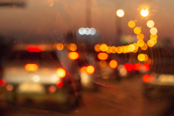 Blurry photo of an evening glowing freeway through a car window. Selective focus macro shot with shallow DOF