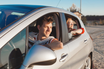 Pretty young couple driving the car at sea shore. Woman and man having fun at the trip. People traveling on automobile.