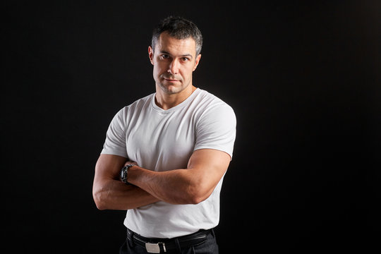 Handsome Athletic man in white blank t-shirt standing on black wall background