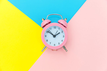 Ringing twin bell classic alarm clock isolated on blue yellow pink pastel colorful geometric...