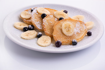 pancakes with banana and blueberries on a white plate, tasty and beautiful on a white background