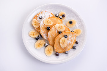 pancakes with banana and blueberries on a white plate, tasty and beautiful on a white background