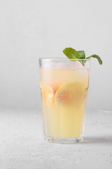 Summer refreshing lemonade with mint on a light background. A glass of citrus cocktail in a light key. Close up. Summer Vitamin cocktail of orange, lemon and grapefruit.