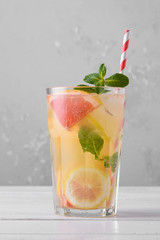 Summer refreshing lemonade with mint on a light background. A glass of citrus cocktail in a light key. Close up. Summer Vitamin cocktail of orange, lemon and grapefruit.