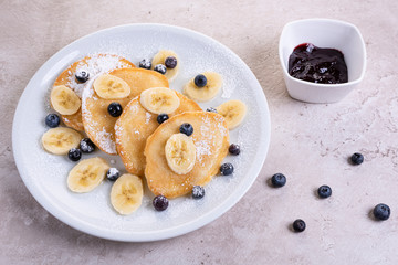 pancakes with banana and blueberries on a white plate, tasty and beautiful