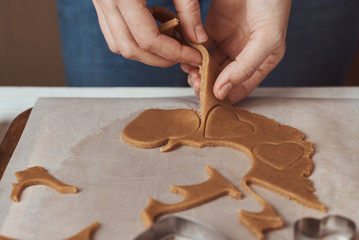 Making gingerbread cookies in the shape of a heart for Valentines Day. Woman hand use cookie cutter. Holiday food concept