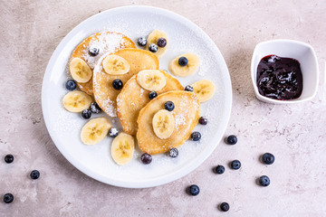 pancakes with banana and blueberries on a white plate, tasty and beautiful