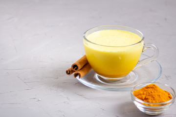 Golden milk in a glass gray cup on a gray background