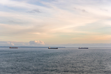 Naklejka na ściany i meble Freight ships anchored on calm sea outside Lisbon in afternoon