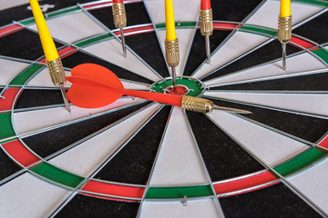 Red and yellow dart arrows hitting in the target center of dartboard. Success hitting target aim...