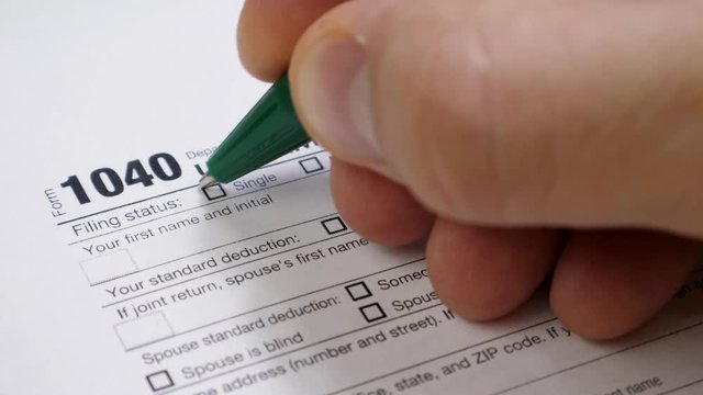 Men's Hand Fills 1040 Tax Form. Indicate Marital Status Single. Write Multiple-Use Name of John Doe. Tax Payers Paperwork Routine and Bureaucracy Concept
