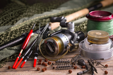 Fishing rods and spinnings in the composition with accessories for fishing on the old background on...