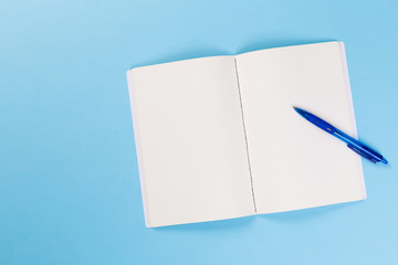 top view of empty open notebook on blue background, office equipment, school supplies and education concept