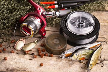 Fishing rods and spinnings in the composition with accessories for fishing on the old background on...