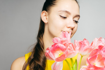 gently lowering her eyes down a very beautiful girl holds a bouquet of tulips in her face