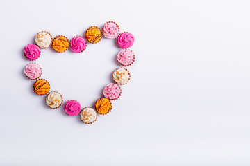Top view Allsorts chocolate Sweets with multicolored cream filling arranged in heart shape on white background isolated. Happy Valentine's day. Love festive concept. Flat lay. Copy space.