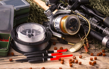 Fishing rods and spinnings in the composition with accessories for fishing on the old background on...