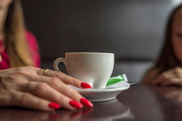 Female hand next to a cup of coffee in a cafe.