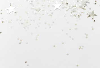 Silver confetti and stars and sparkles on a light background. Top view, flat lay. Copy text. holiday background. For Christmas, New Year, Valentine's Day
