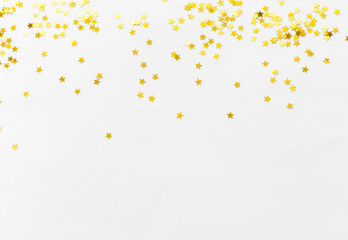 Gold confetti and stars and sparkles on a light background. Top view, flat lay. Copy text. Bright and festive background. For Christmas, New Year, Mother's Day.