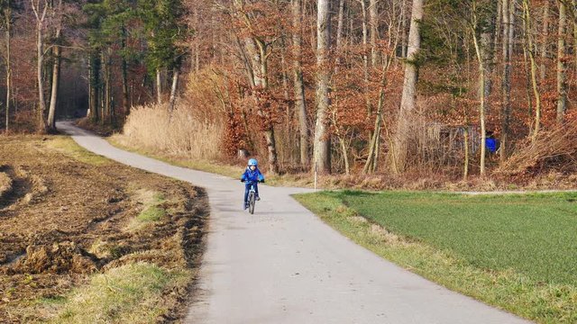 Kleiner Junge f&auml;hrt mit Helm Fahrrad auf einer Landstrasse