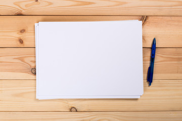 A4 white paper with pen on wooden background. Blank branding template. Photo blank form. Layout for portfolio design.
