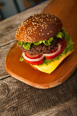 Tasty burger with cheese on wooden table