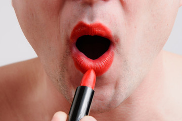 Transevestit guy open the mounth for paints his lips with red lipstick