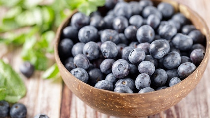 Ripe blueberries in a coconut bowl on old wooden background