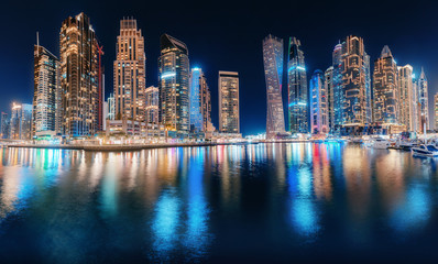 Night colorful view of the famous tourist attraction of the city of Dubai - Marina seaport and illuminated skyscrapers. Travel and real estate in United Arab Emirates