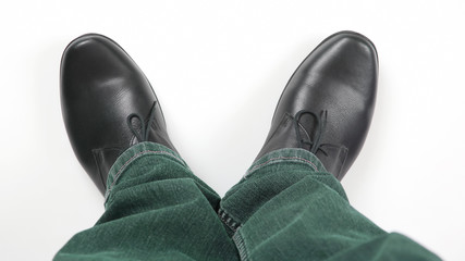 Men's legs in jeans and black classic shoes on white background