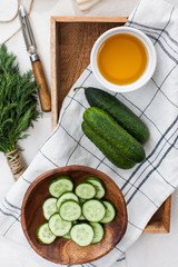 Fresh cucumbers whole and cut into slices in a wooden plate. Foodfoto for ecomarket and menu for vegetarians.
