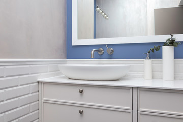 Bathroom interior in a blue pastel colors and bathroom furniture. A bowl-shaped sink on a ultra thin quartzite countertop. Contemporary bathroom design. 
