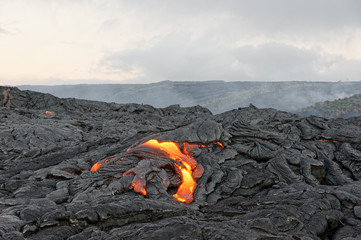 Hot magma of an active lava flow emerges from a fissure, the heat of the glowing lava makes the air flicker, the lava cools down slowly and solidifies - Hawaii, Big Island, Kilauea volcano, Kalapana