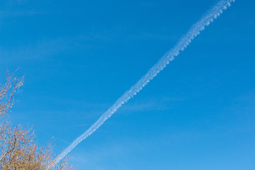 Fototapeta na wymiar Chemtrails or Contrials high above the sky visible on a clear blue day
