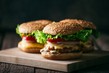 Fresh tasty grilled beef burgers with cheese wood background.